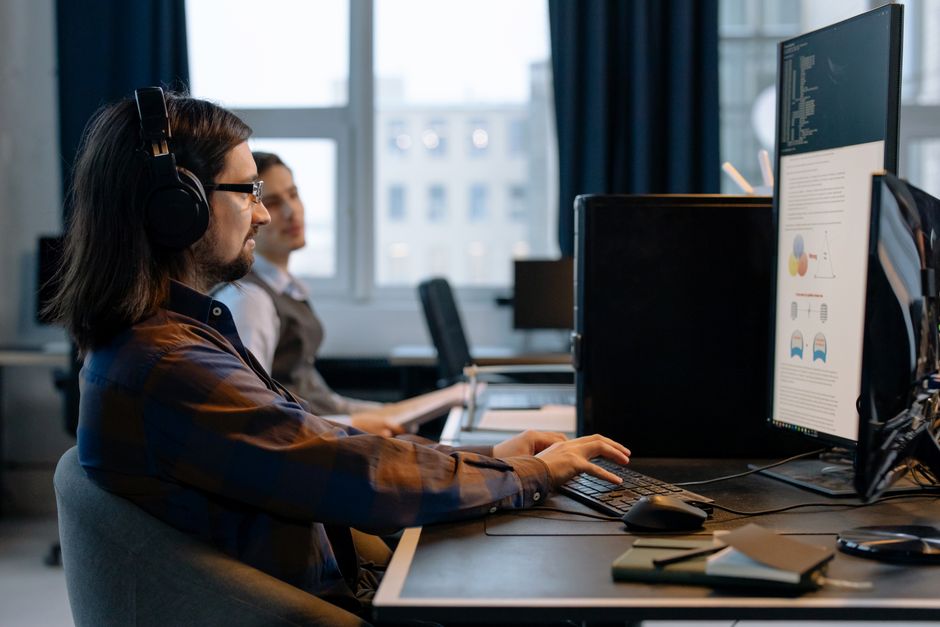 Dos programadores trabajando juntos con enfoque en codificación en un entorno de oficina tecnológico moderno.