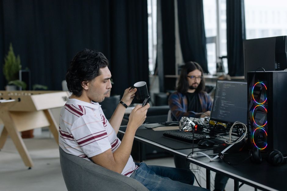 Dos programadores trabajando, enfocados en la codificación y disfrutando de un café
