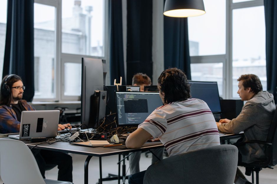 Equipo de desarrolladores trabajando juntos en computadoras en una oficina tecnológica moderna.