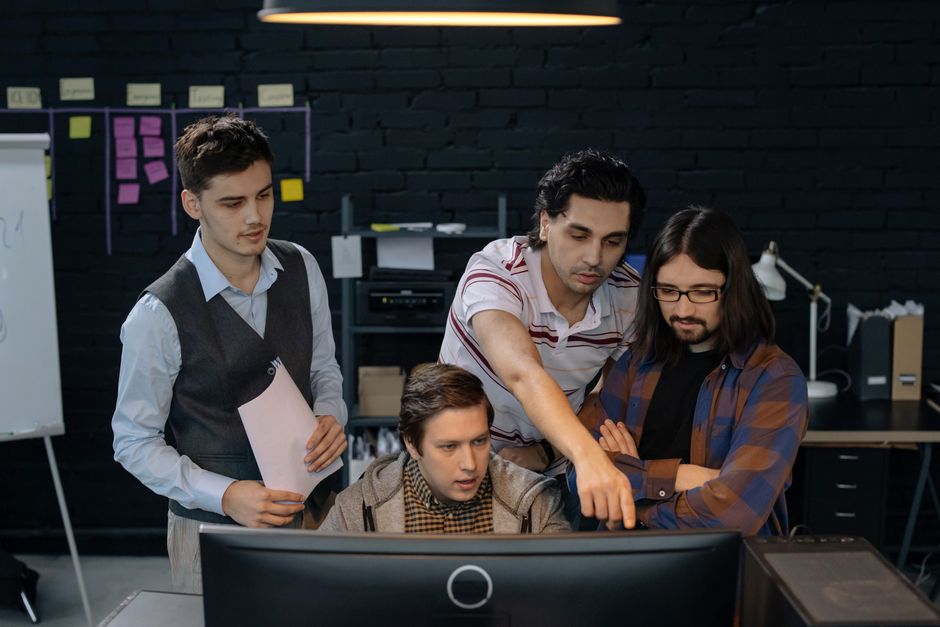 Grupo de profesionales discutiendo un proyecto en una computadora en un entorno de oficina moderno